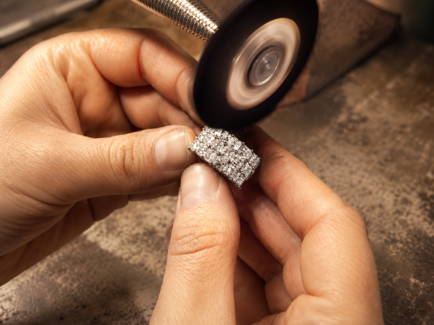 Jeweller inspecting a piece of jewellery at the workshop bench